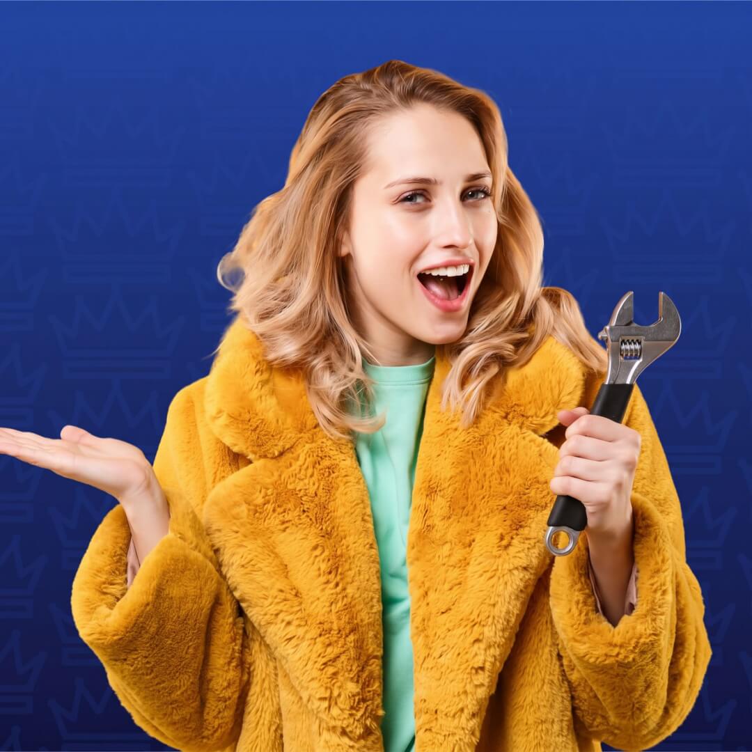 Smiling woman in a yellow fur coat holding a large adjustable wrench against a blue background